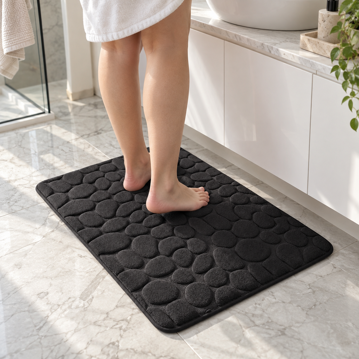 Black cobblestone bath mat in front of a bathroom vanity