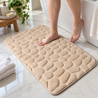 Cream cobblestone bath mat beside a freestanding bathtub