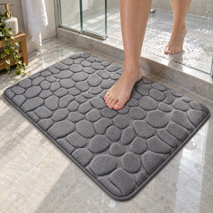 Gray cobblestone bath mat outside a glass walk-in shower
