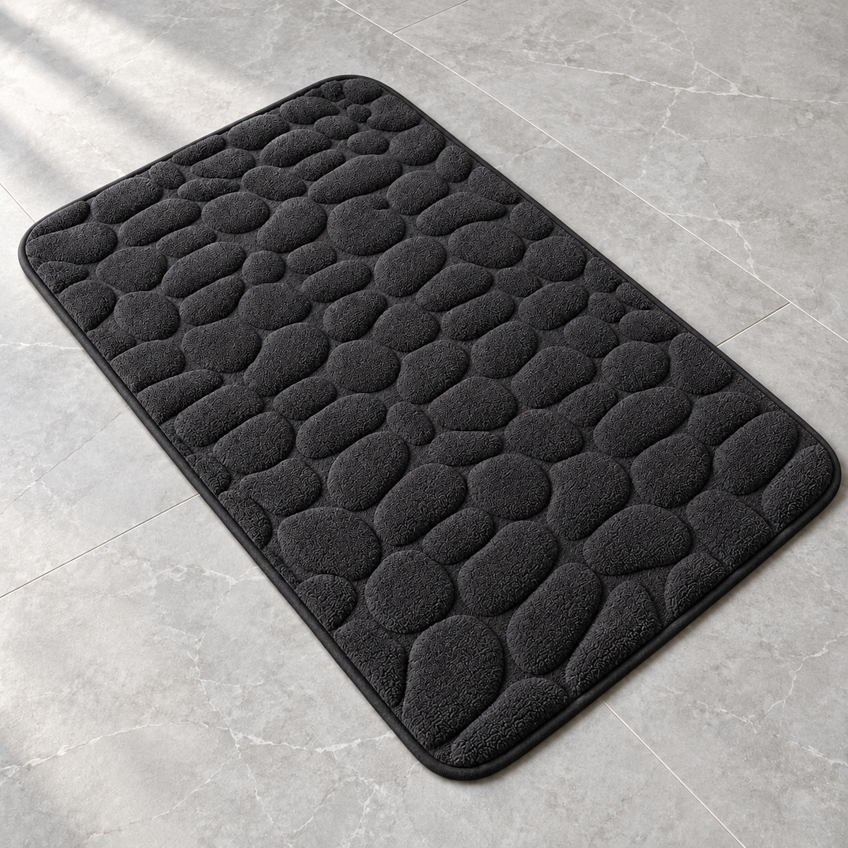 Black 3D cobblestone non-slip bath mat on a bathroom floor