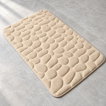 Cream 3D cobblestone non-slip bath mat on a bathroom floor