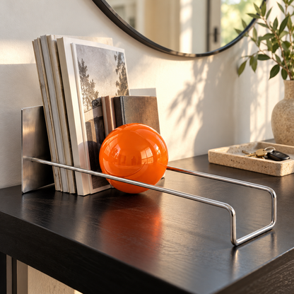 Orange sphere book holder on a black entryway console