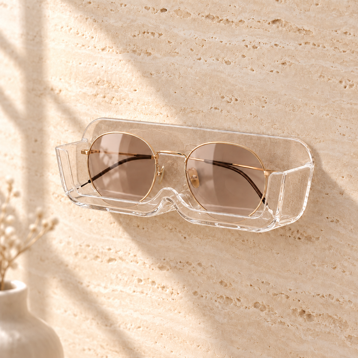 Clear acrylic stick-on wall glasses holder with gold-rim sunglasses on a travertine wall