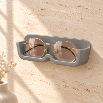Gray stick-on wall glasses holder with gold-rim sunglasses on a travertine wall