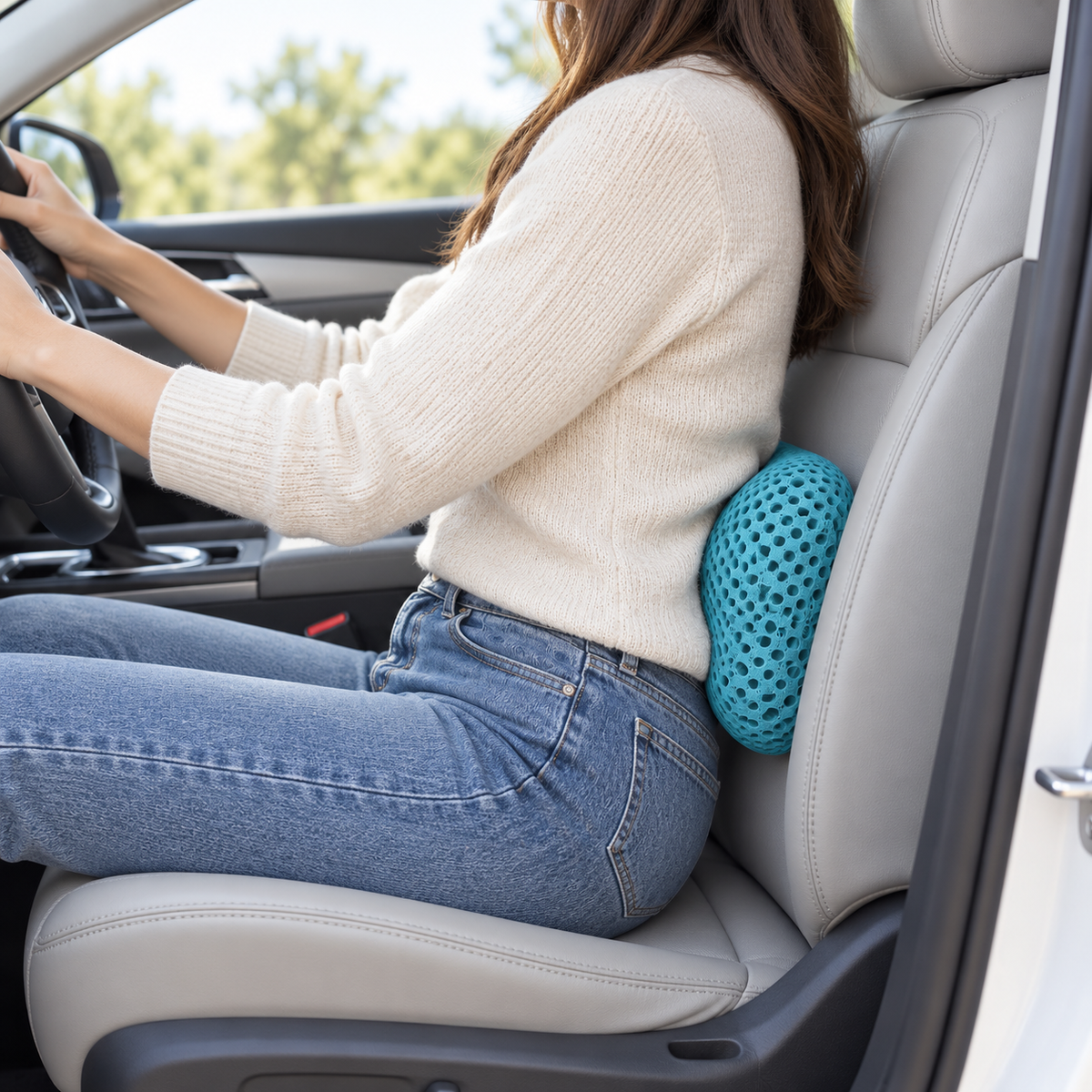 Driver with a lumbar support pillow between her lower back and the car seat