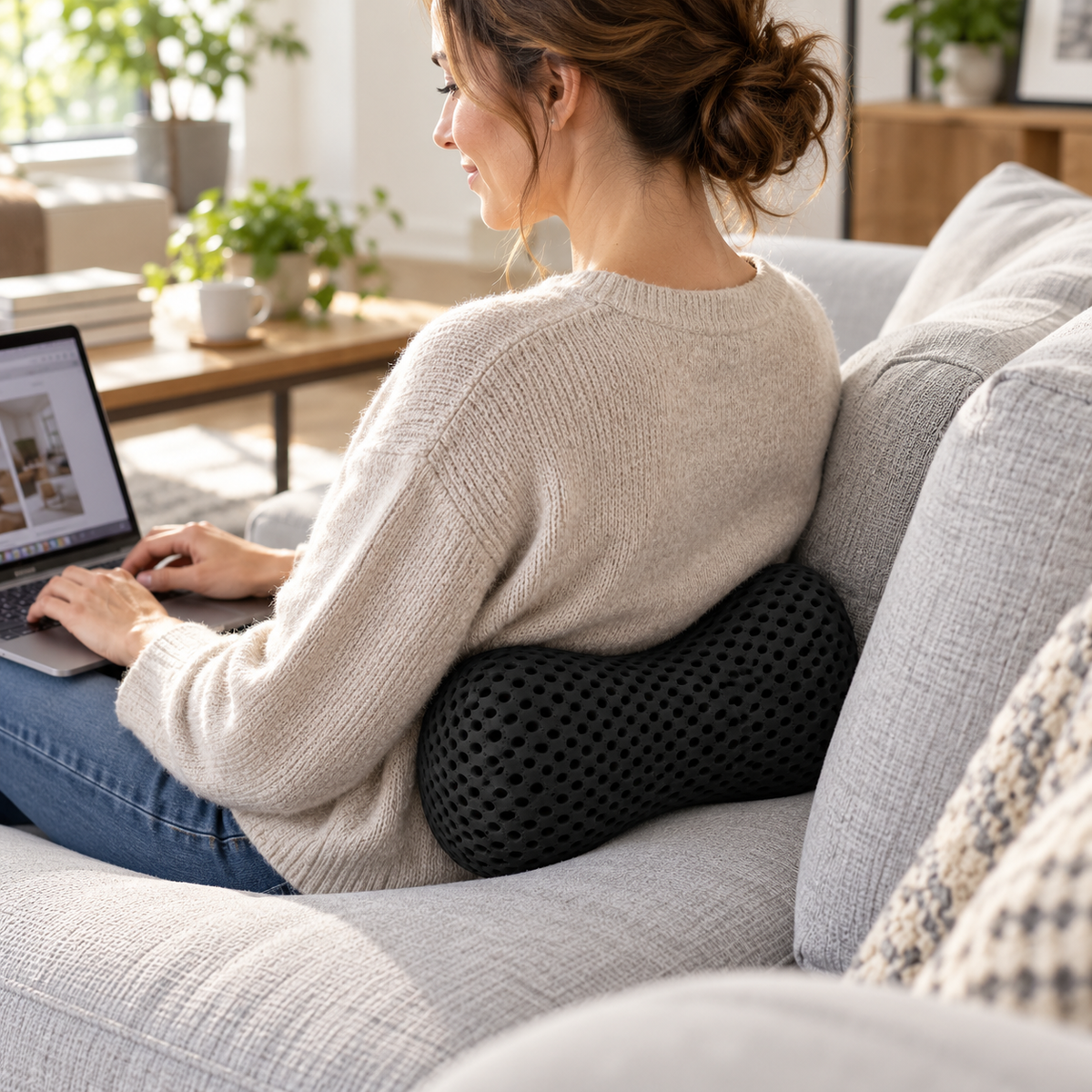 Woman on a sofa with a small lumbar pillow supporting her lower back