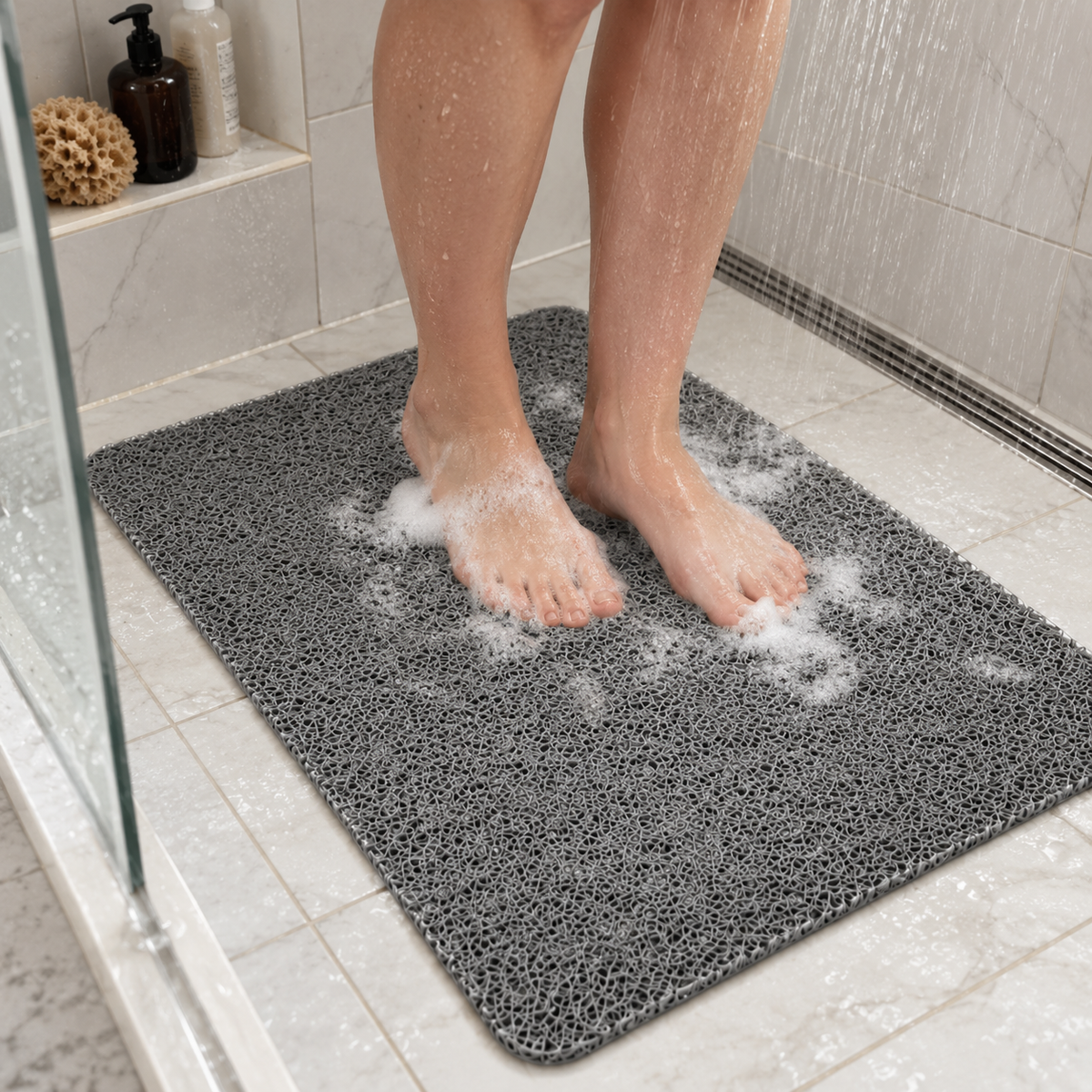 Feet standing on a gray loofah shower mat in a walk-in shower