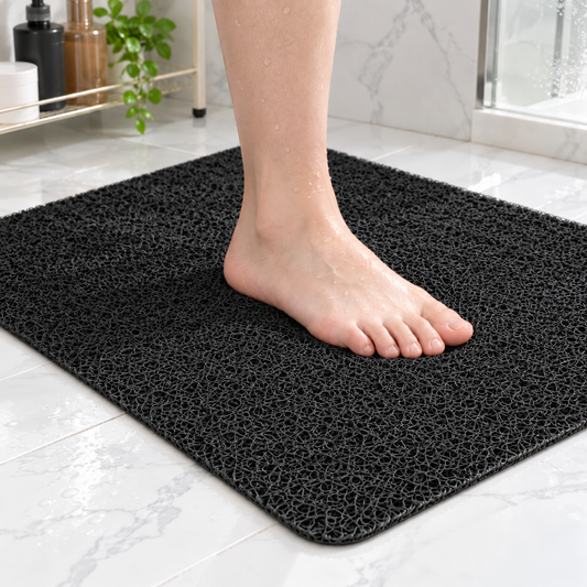 Bare foot standing on a black loofah shower mat