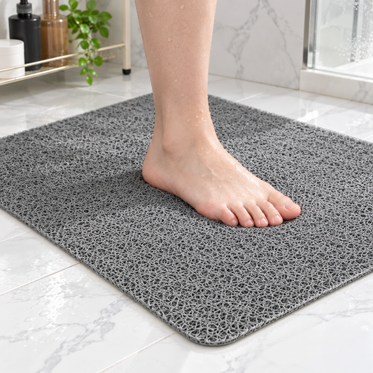 Bare foot standing on a gray loofah shower mat